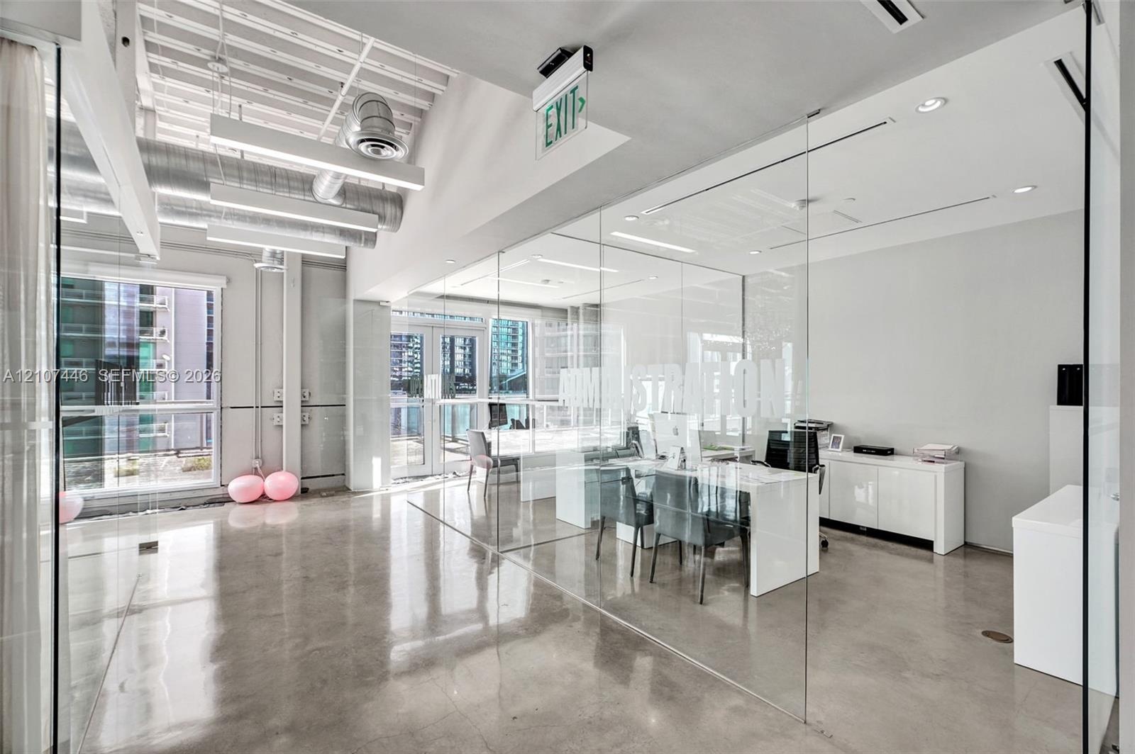 Polished concrete flooring, exposed ceiling ductwork, floor-to-ceiling glass wall partitions, and expansive windows