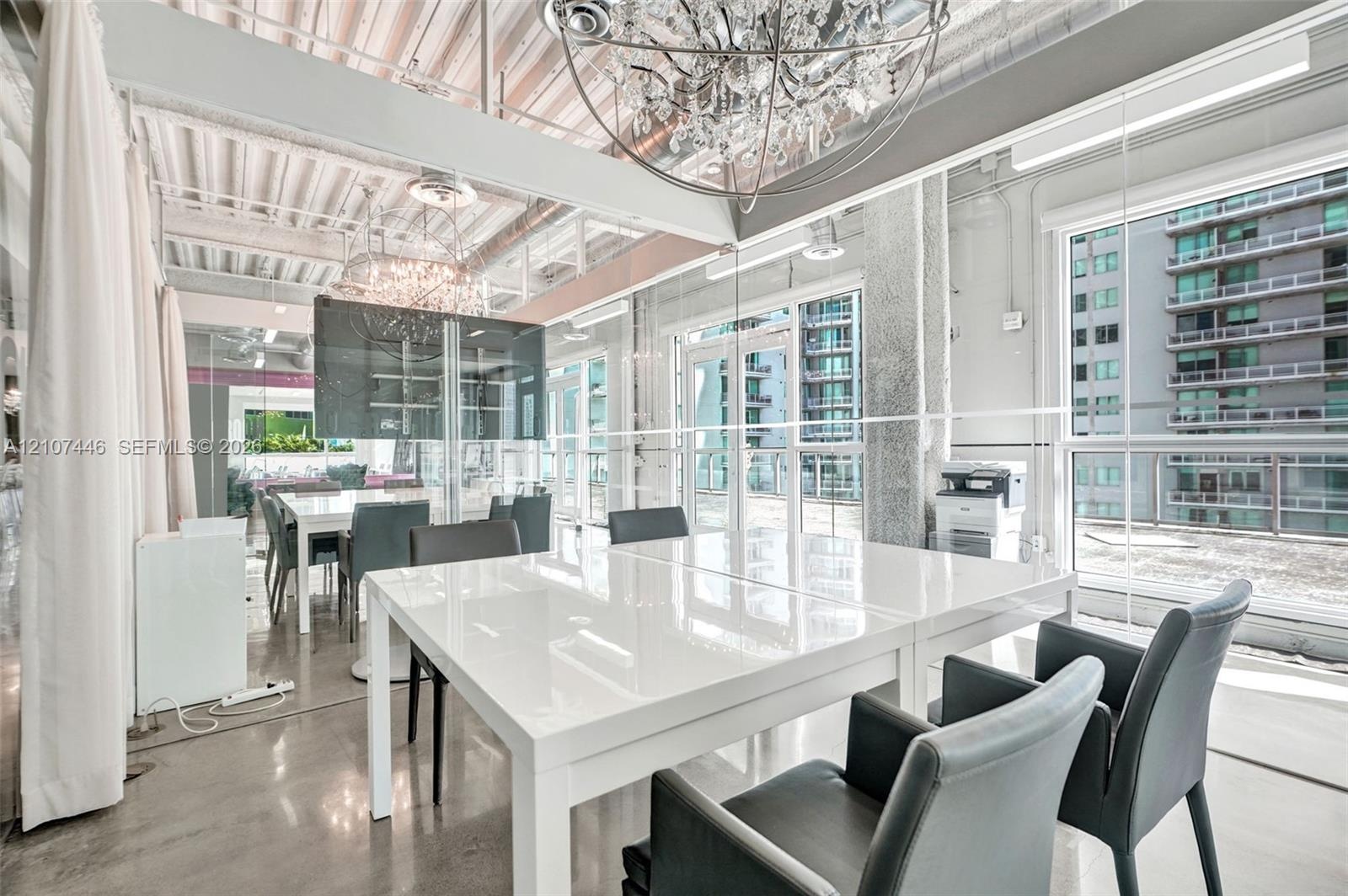 Industrial-style interior featuring exposed corrugated metal ceiling, expansive glass curtain walls, polished concrete flooring, and oversized crystal
