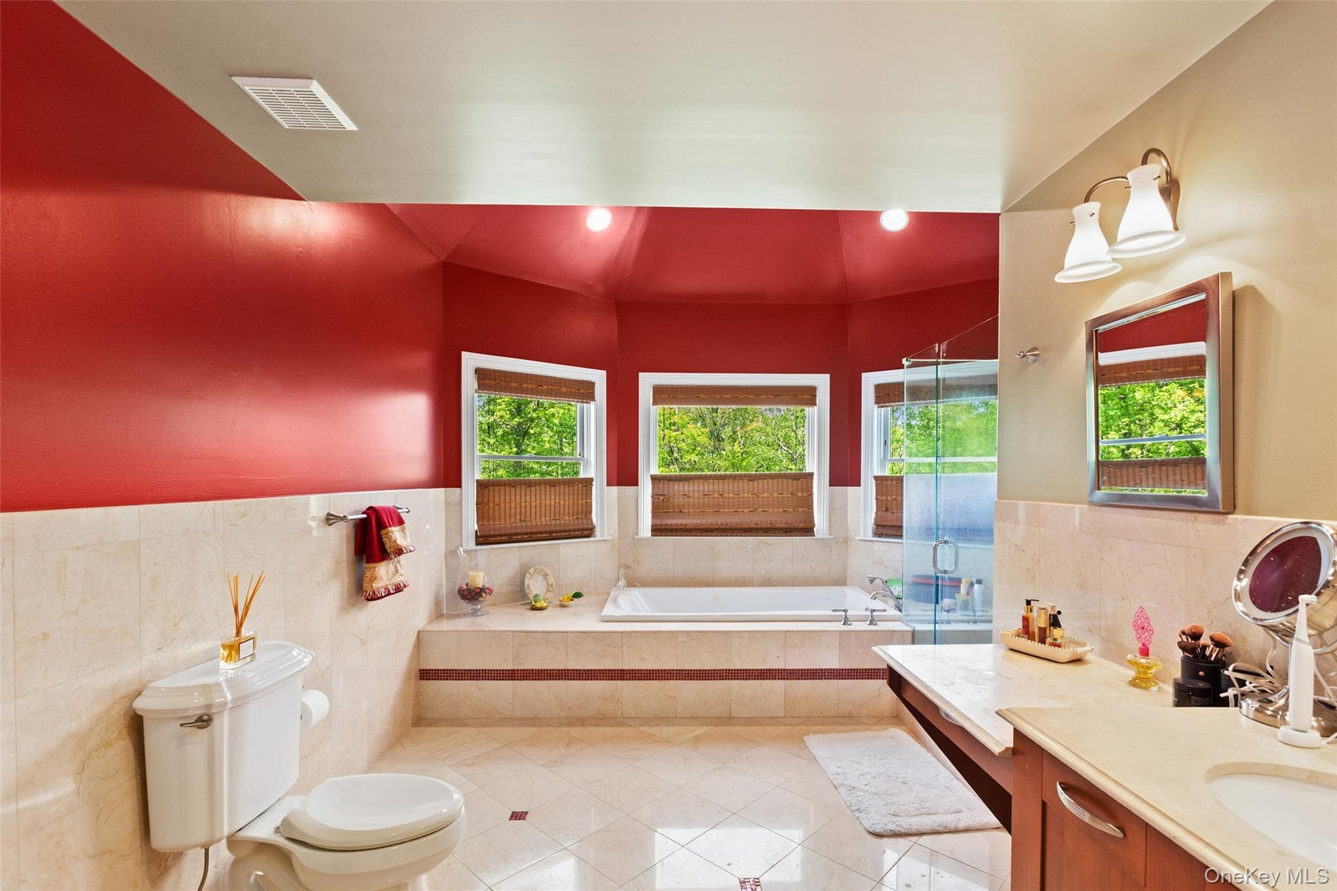 Featuring tile patterned flooring, vanity, a garden tub, plenty of natural light, and tile walls