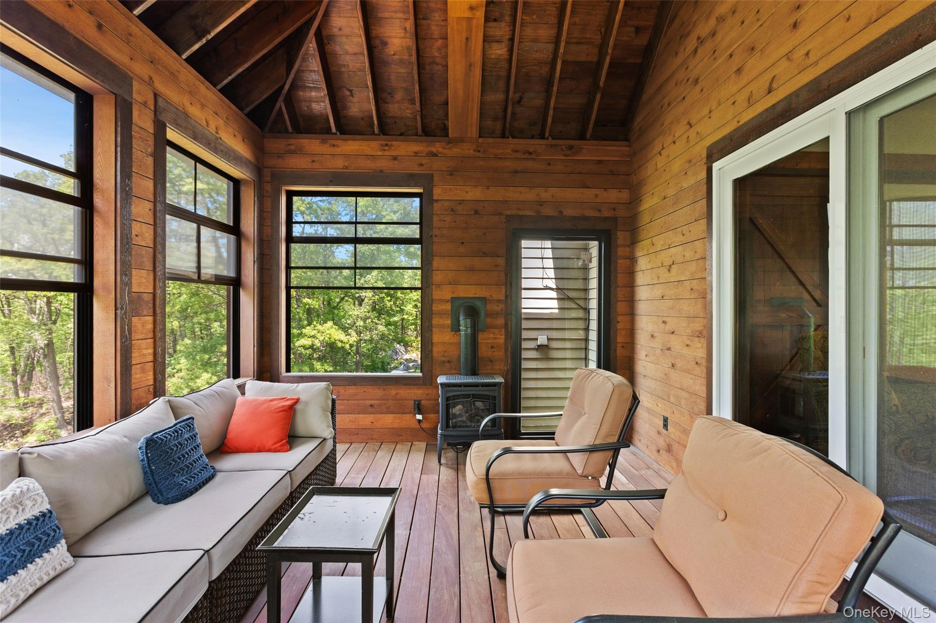 Sunroom / solarium with wood ceiling, wooden walls, a wood stove, and hardwood / wood-style floors