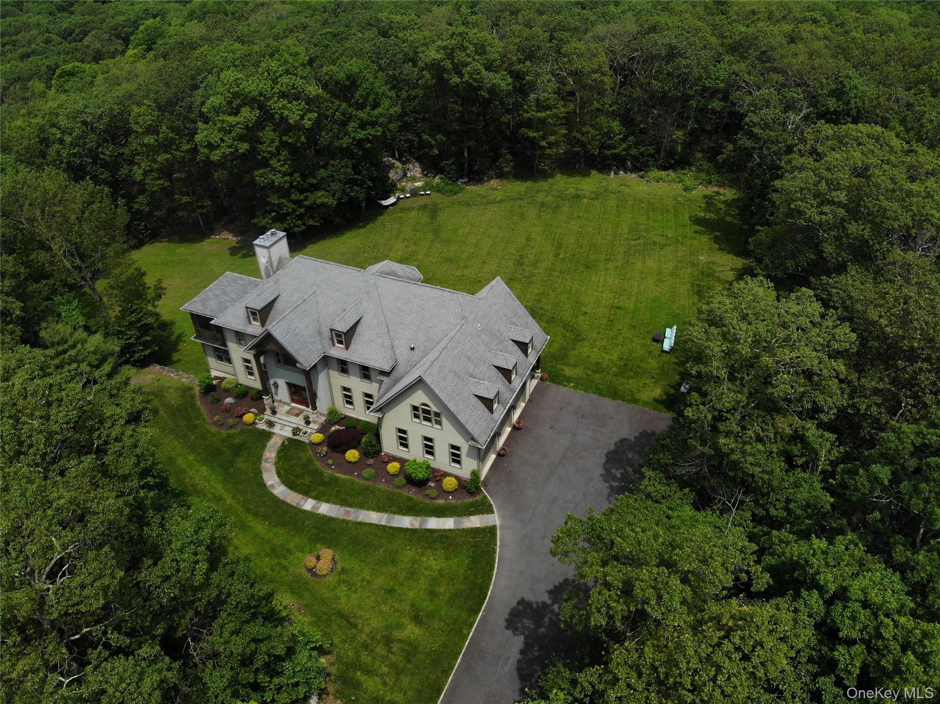 Aerial view of property and surrounding area with a heavily wooded area