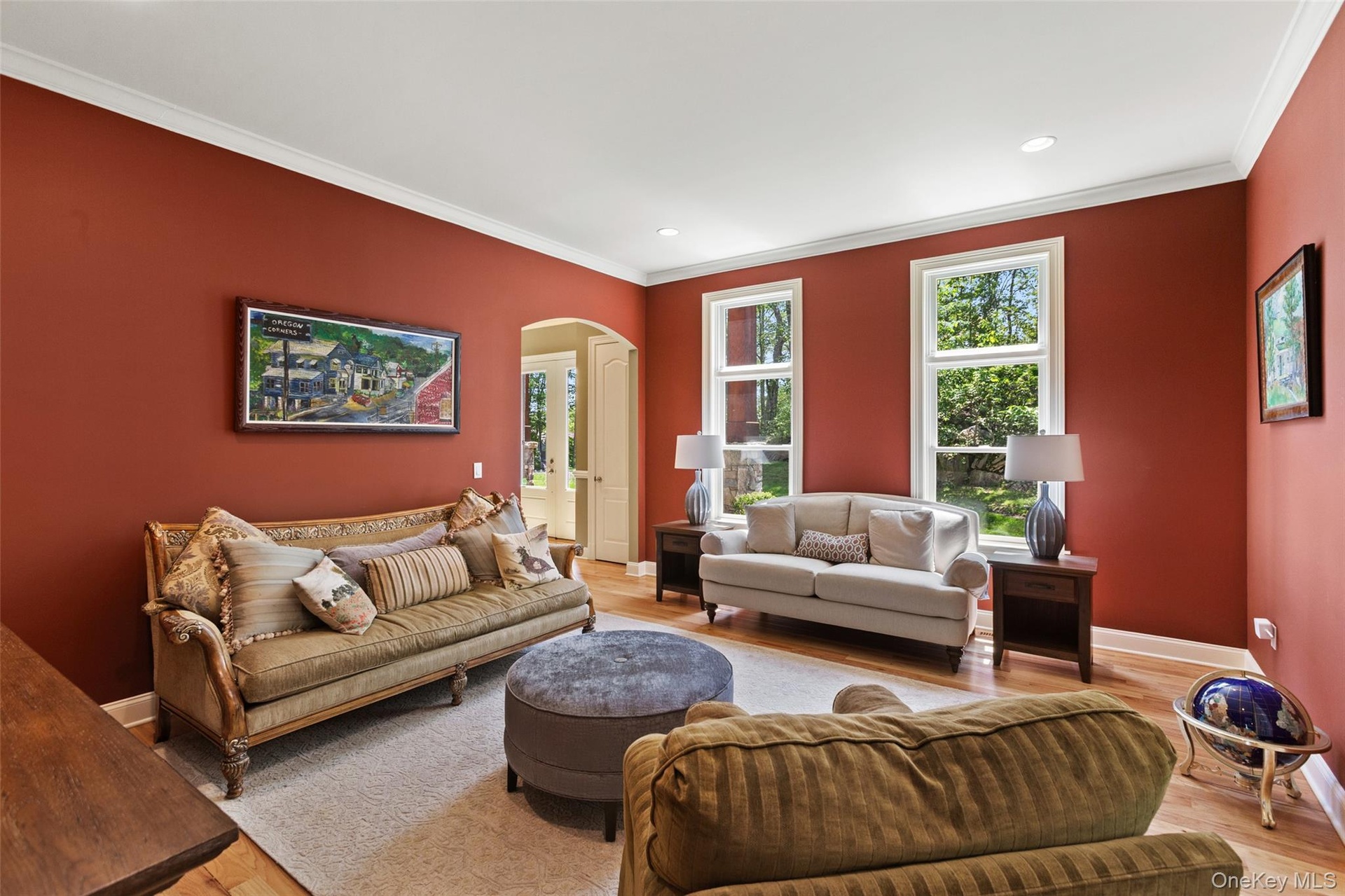 Living area featuring arched walkways, crown molding, light wood finished floors, baseboards, and recessed lighting