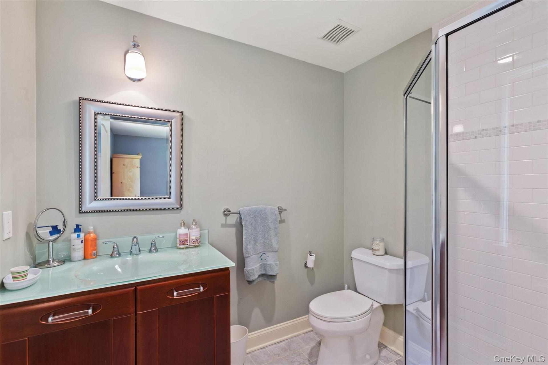 Full bath with toilet, vanity, a stall shower, and baseboards