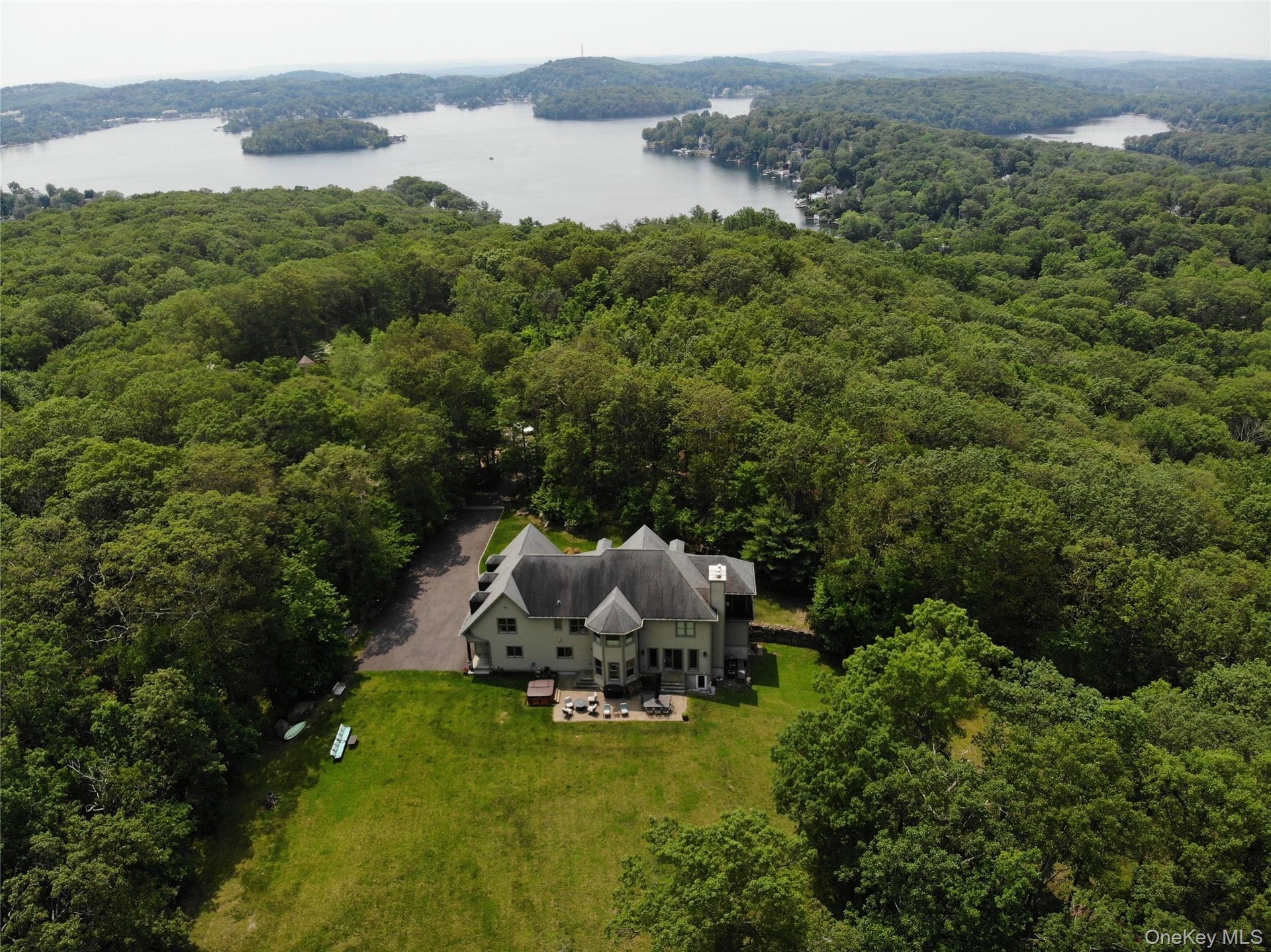 Aerial view of the property with a heavily wooded area and nearby "LAKE MAHOPAC"