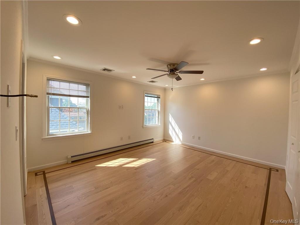 Spare room featuring ceiling fan, baseboard heating, hardwood / wood-style flooring, and ornamental molding