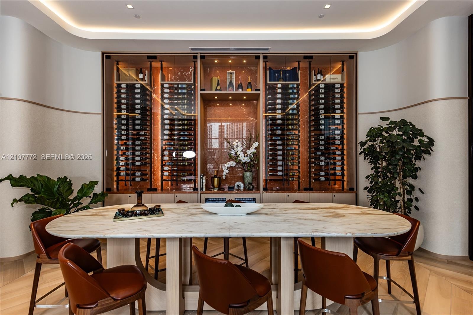 Custom built-in glass-front wine display with integrated accent lighting and natural stone-finish back panel, featuring curved wall detailing and chev