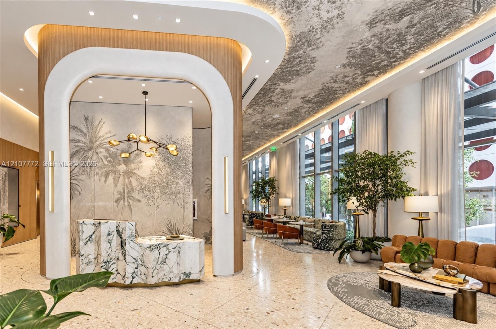 Grand lobby featuring floor-to-ceiling windows, arched architectural detailing with wood-finish paneling, a textured stone reception desk, integrated 