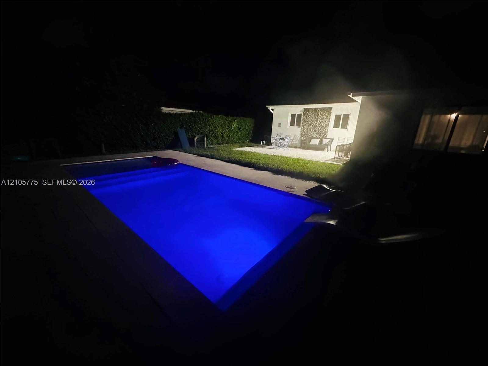Inground swimming pool with concrete decking, manicured lawn, and perimeter landscaping