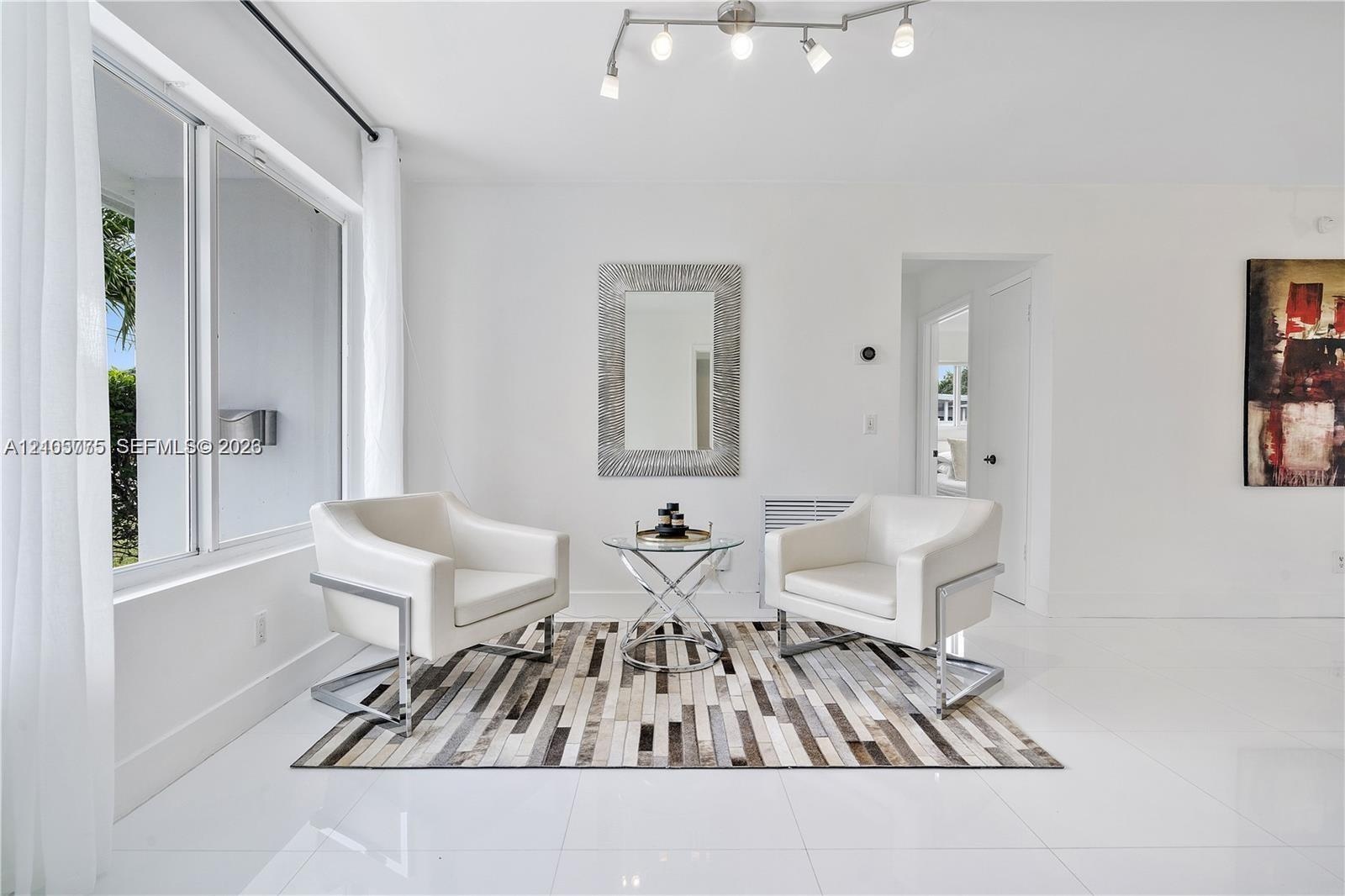 Bright interior space featuring polished tile flooring, large multi-pane windows, and a multi-bulb track lighting fixture