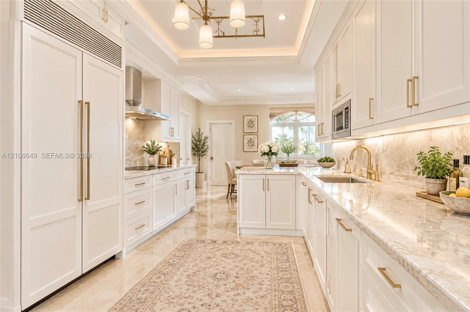 Kitchen featuring custom white cabinetry, integrated panel-ready refrigerator, stone countertops, under-cabinet lighting, and tray ceiling with recess