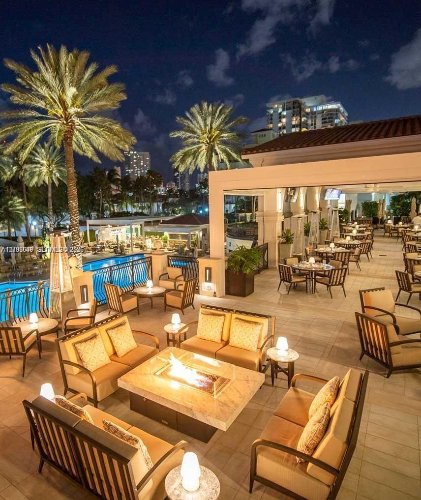 Expansive outdoor terrace featuring stone flooring, a built-in fire pit with a stone surround, and an integrated swimming pool with metal safety raili
