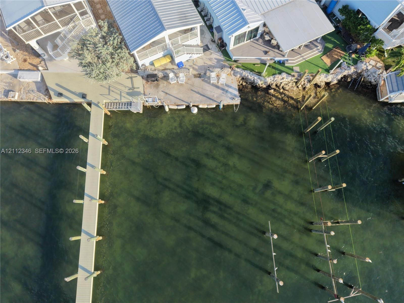 Waterfront property featuring a private boat dock, extended pier, bulkhead hardscaping, and metal roofing