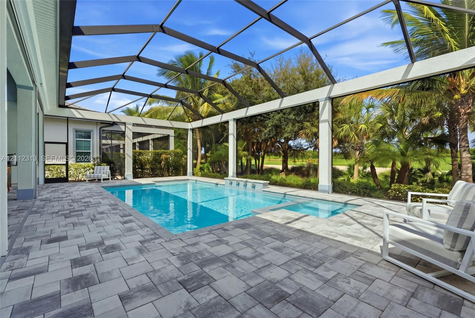 Screened-in lanai featuring a paver patio, swimming pool, integrated spa, and fountain spillway