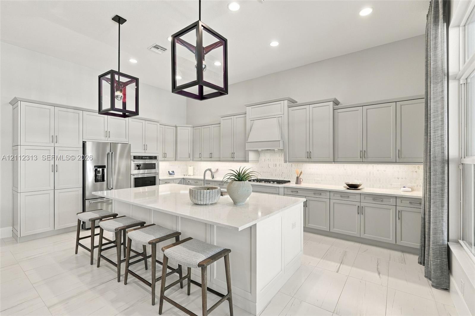 Kitchen featuring shaker-style cabinetry, quartz countertops, a central island, recessed lighting, and geometric pendant fixtures