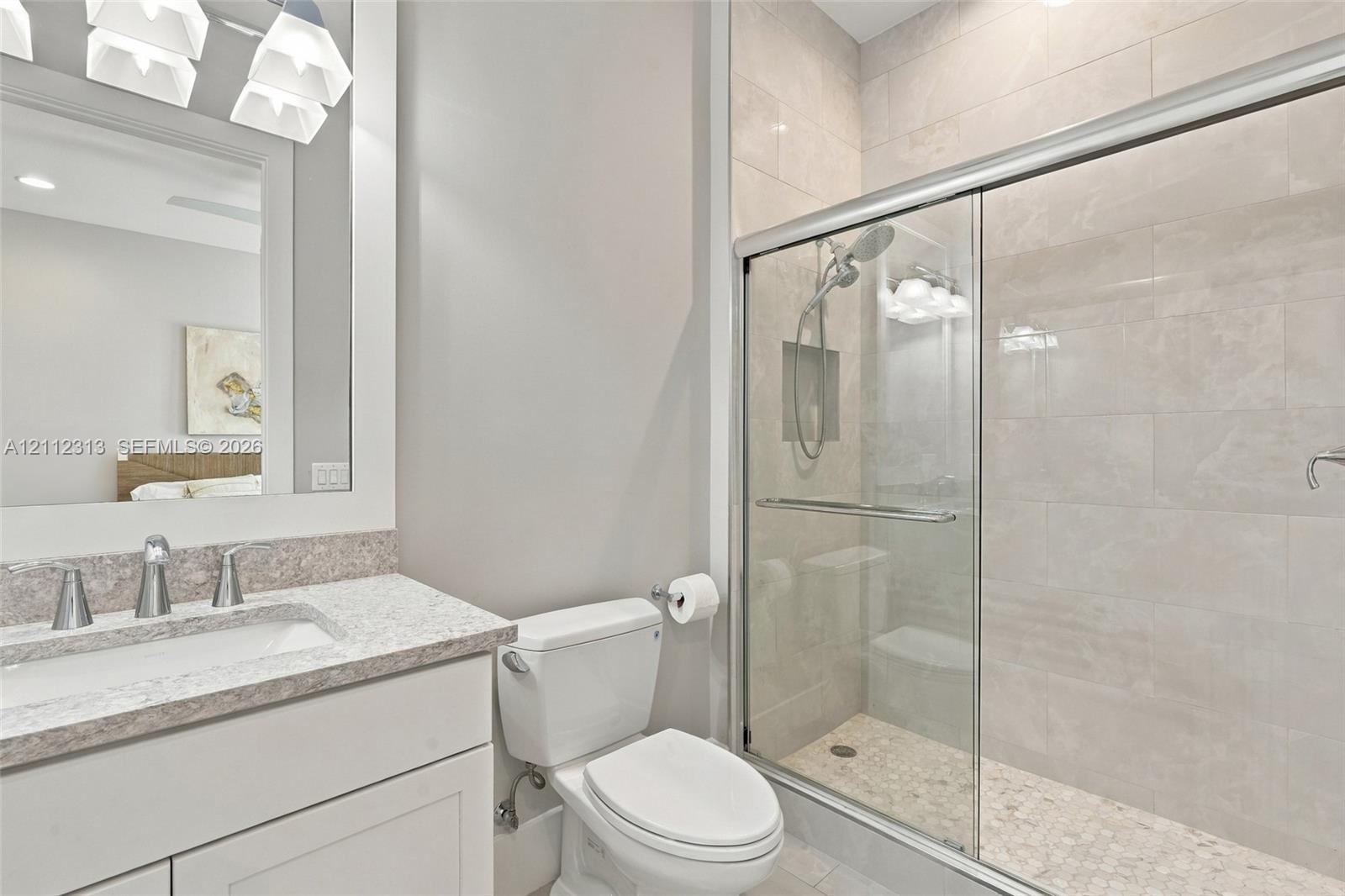 Bathroom featuring a vanity with a light-toned countertop, a frameless glass-enclosed shower with tiled walls and a built-in recessed niche, and polis
