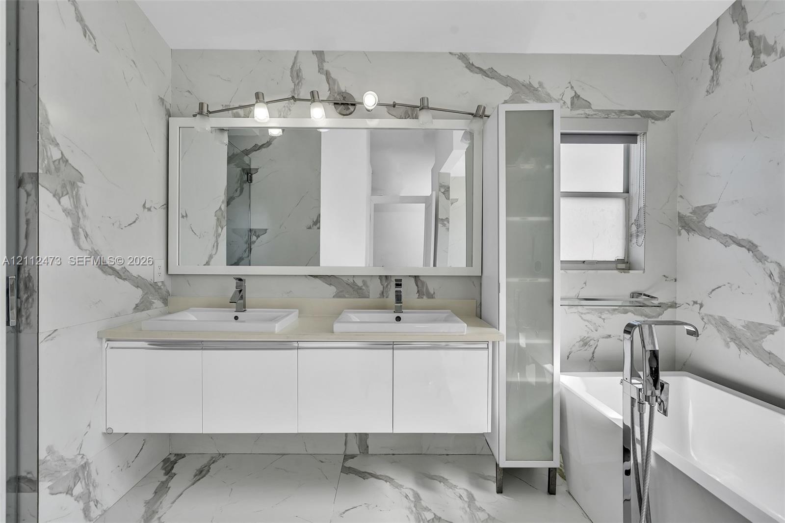 Floating double vanity with integrated rectangular sinks, stone-finish countertop, full-height frosted glass cabinetry, and floor-to-ceiling vein-patt