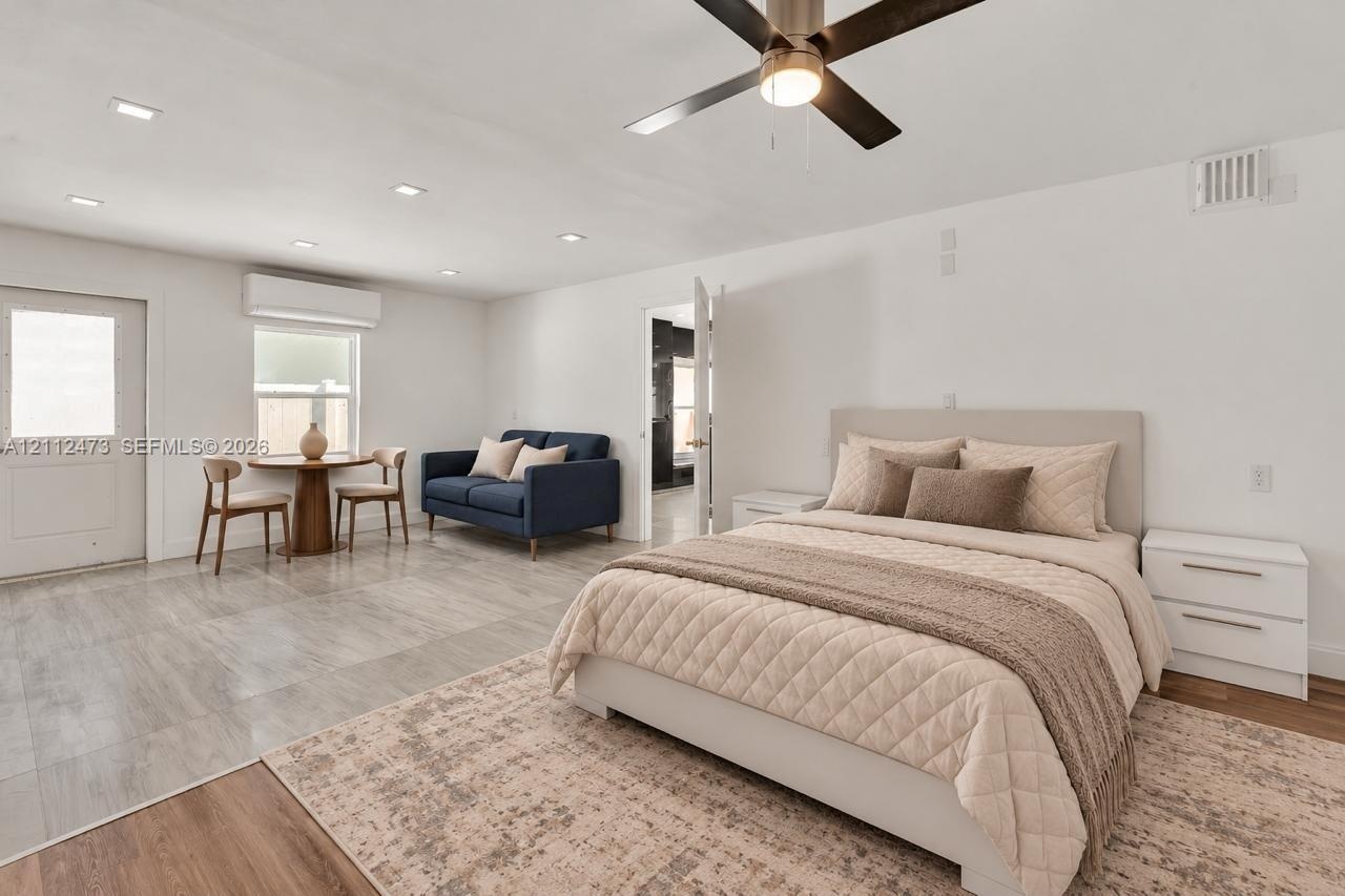 Neutral-toned room featuring stone-finish flooring, recessed lighting, a modern ceiling fan, and a wall-mounted ductless heating and cooling unit