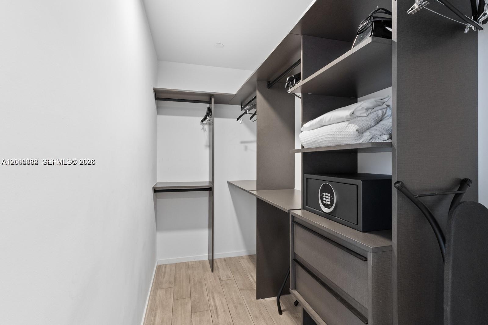 Custom closet system featuring dark wood-finish cabinetry, integrated shelving, hanging rods, and two soft-close drawers, complemented by wood-finish 