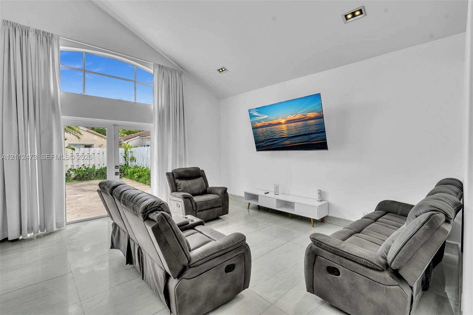Vaulted ceilings, large-format tile flooring, recessed lighting, and expansive floor-to-ceiling glass panel doors