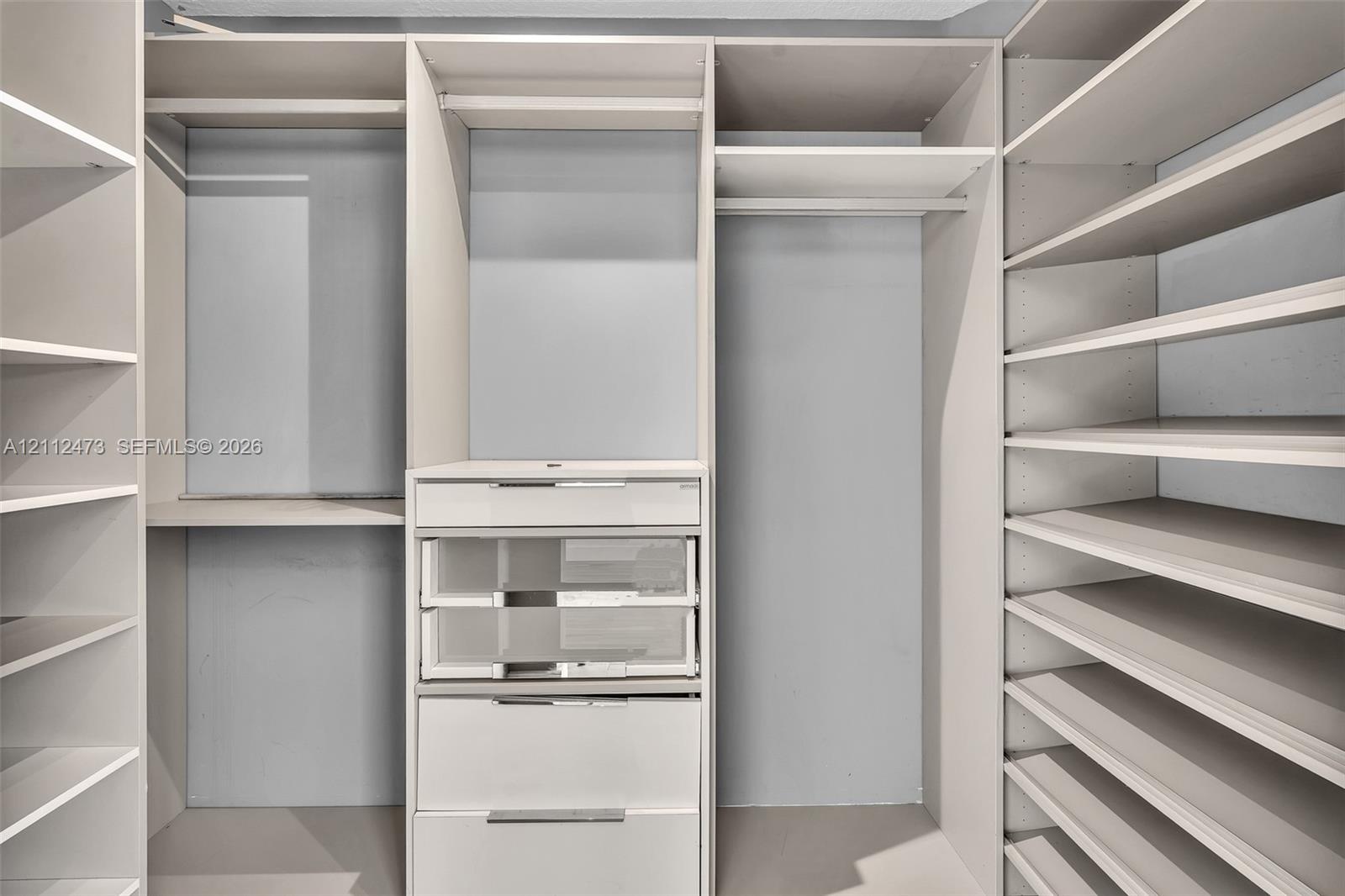 Customized closet organization system featuring adjustable shelving, integrated garment rods, and built-in drawers with glass-front paneling