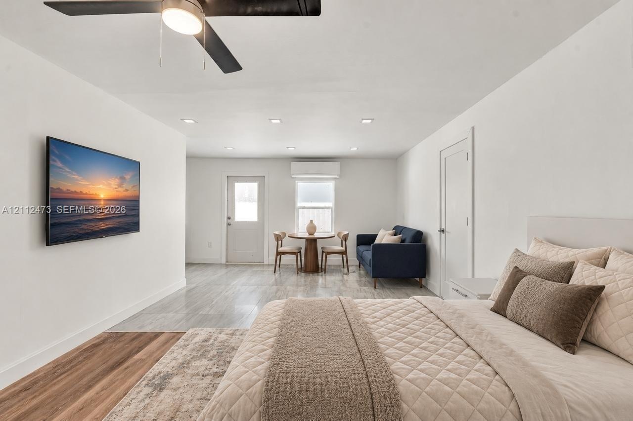 Open-concept space featuring recessed ceiling lighting, wood-finish flooring, a wall-mounted ductless climate control unit, and a ceiling fan