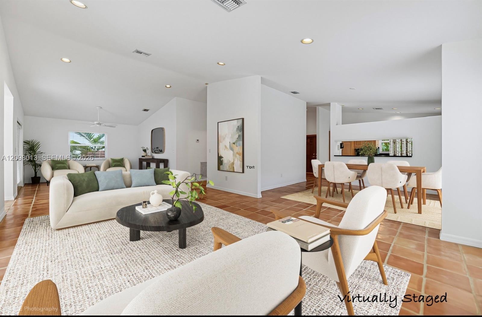 Open-concept interior featuring vaulted ceilings. Virtually staged photo