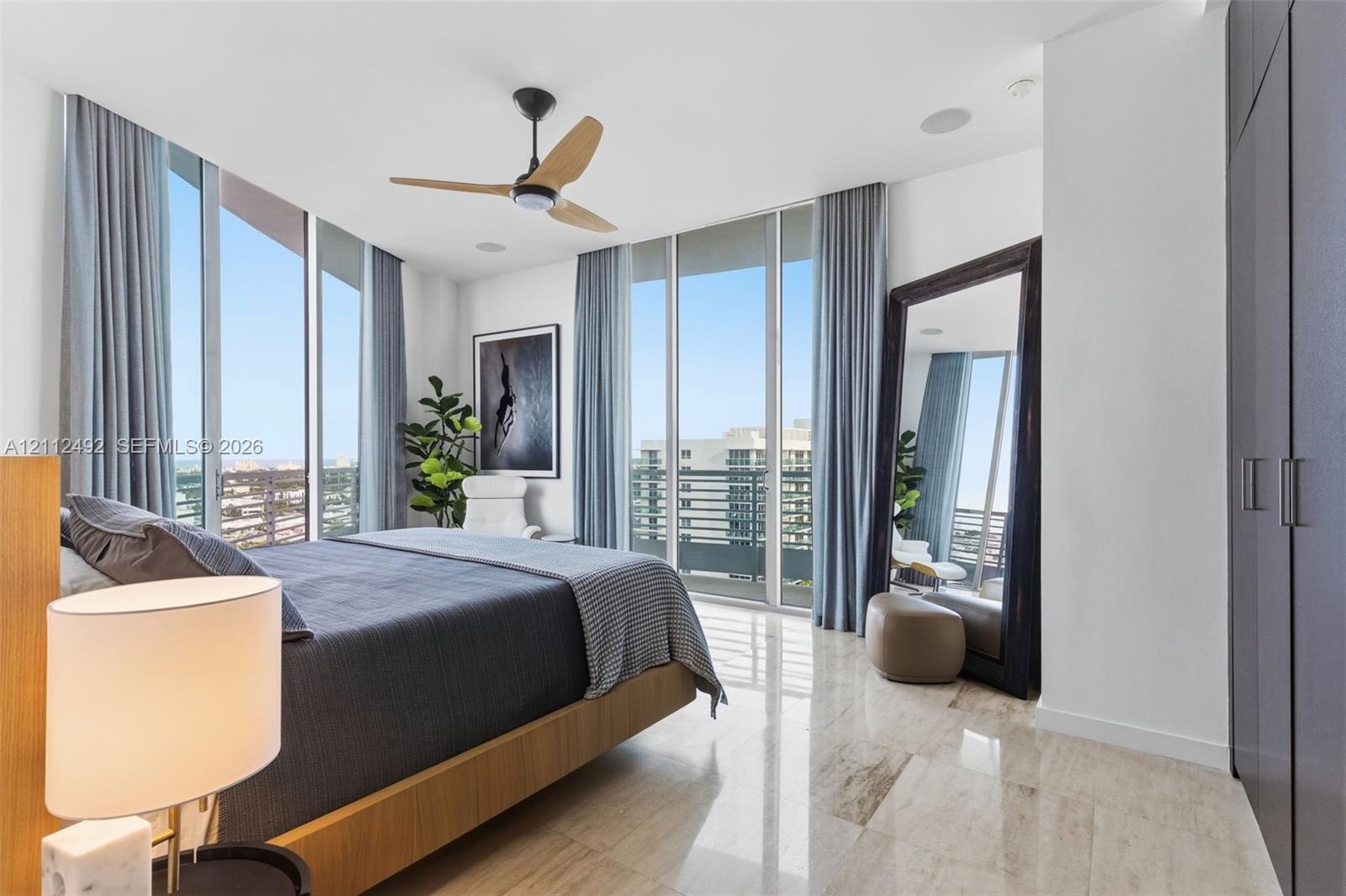 Floor-to-ceiling windows, polished stone flooring, dark built-in cabinetry, and a ceiling fan with light fixture