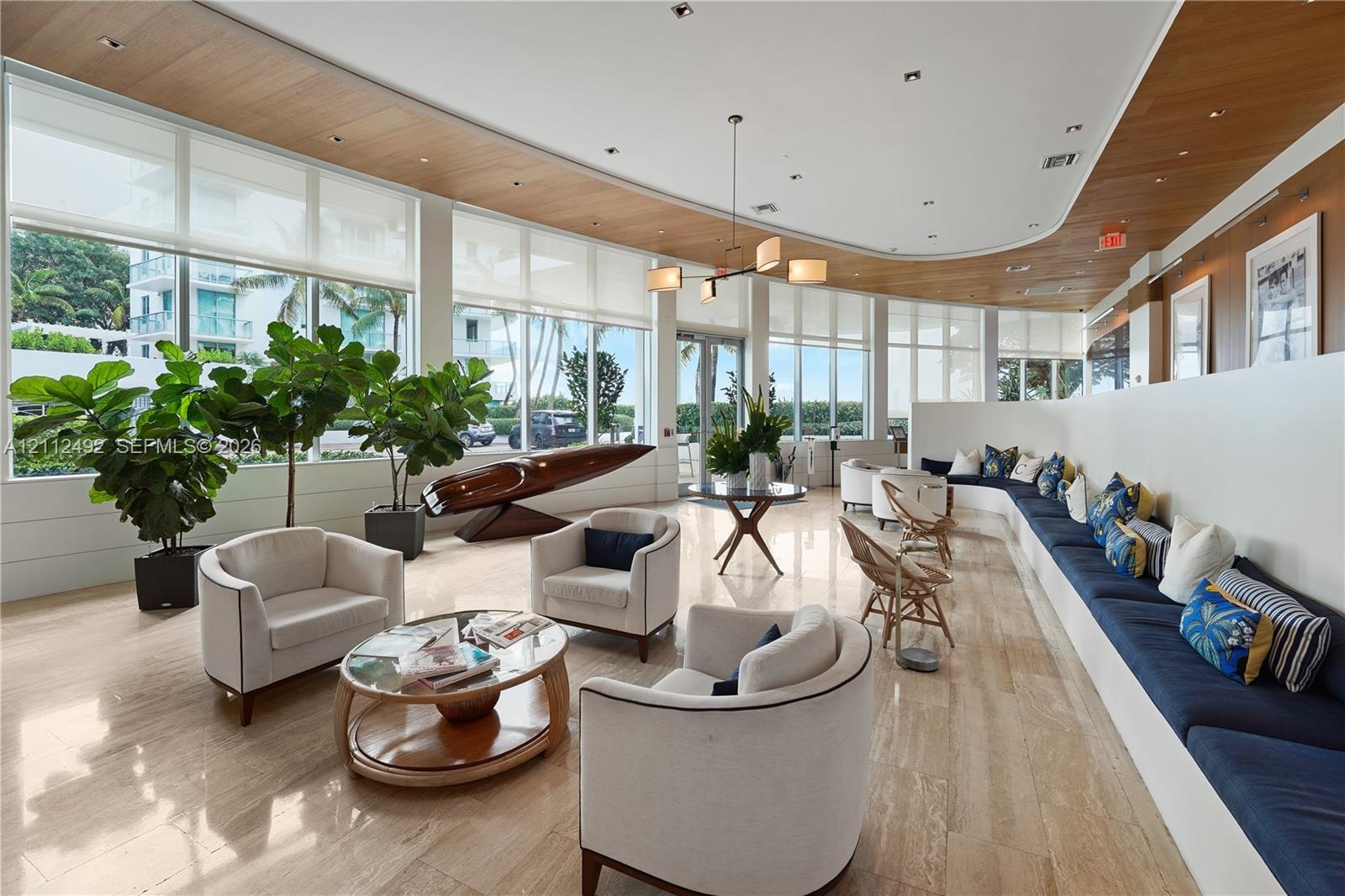 Floor-to-ceiling windows with integrated roller shades, stone flooring, curved wood-paneled ceiling, custom built-in bench seating, and multi-arm chan