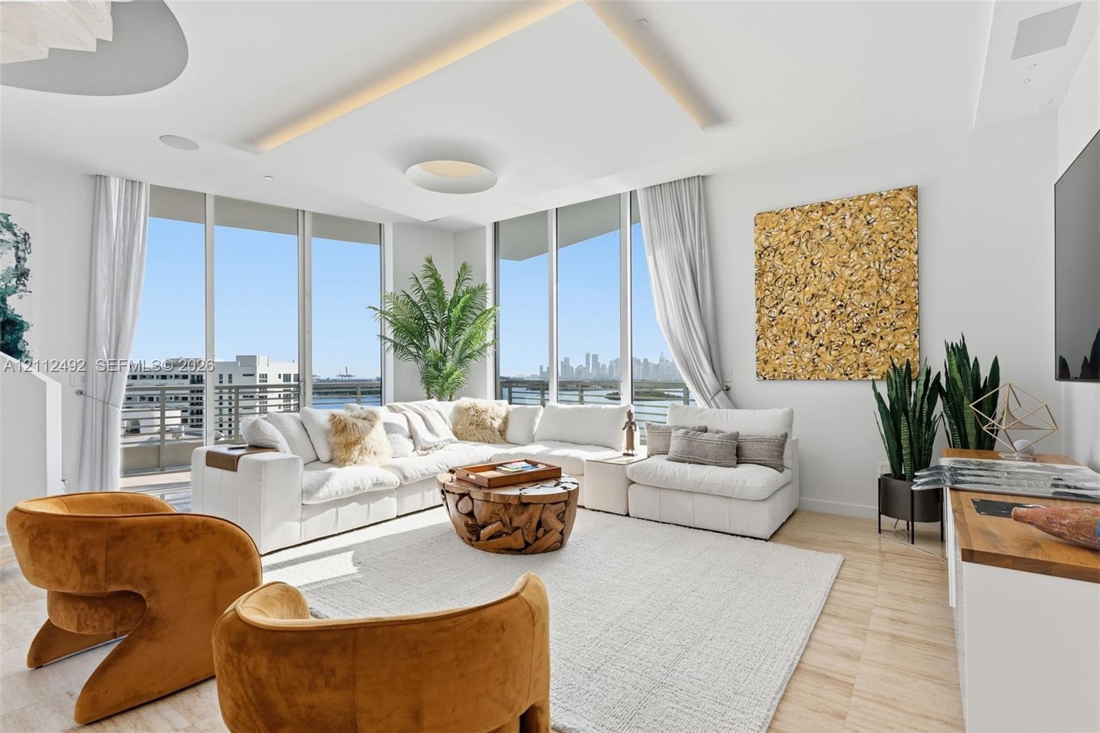 Floor-to-ceiling windows, recessed cove lighting, wood-finish flooring, and a private balcony