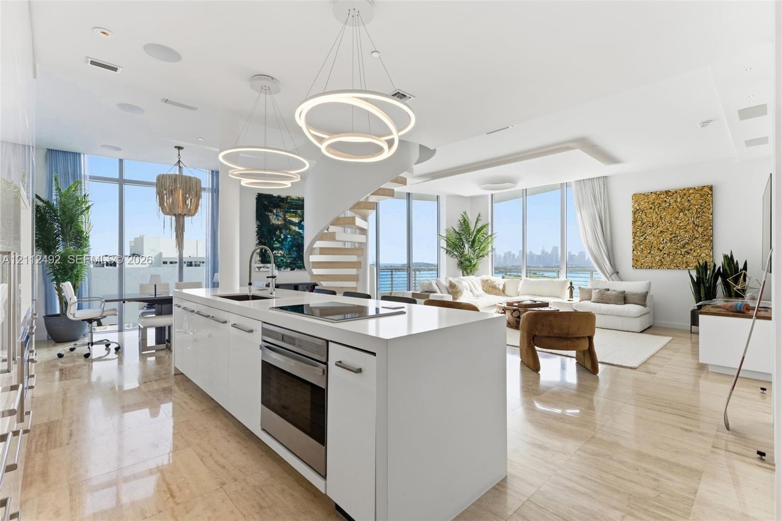 Open concept kitchen featuring a stone-topped island, stainless steel built-in oven, contemporary ring chandeliers, polished stone flooring, and a str
