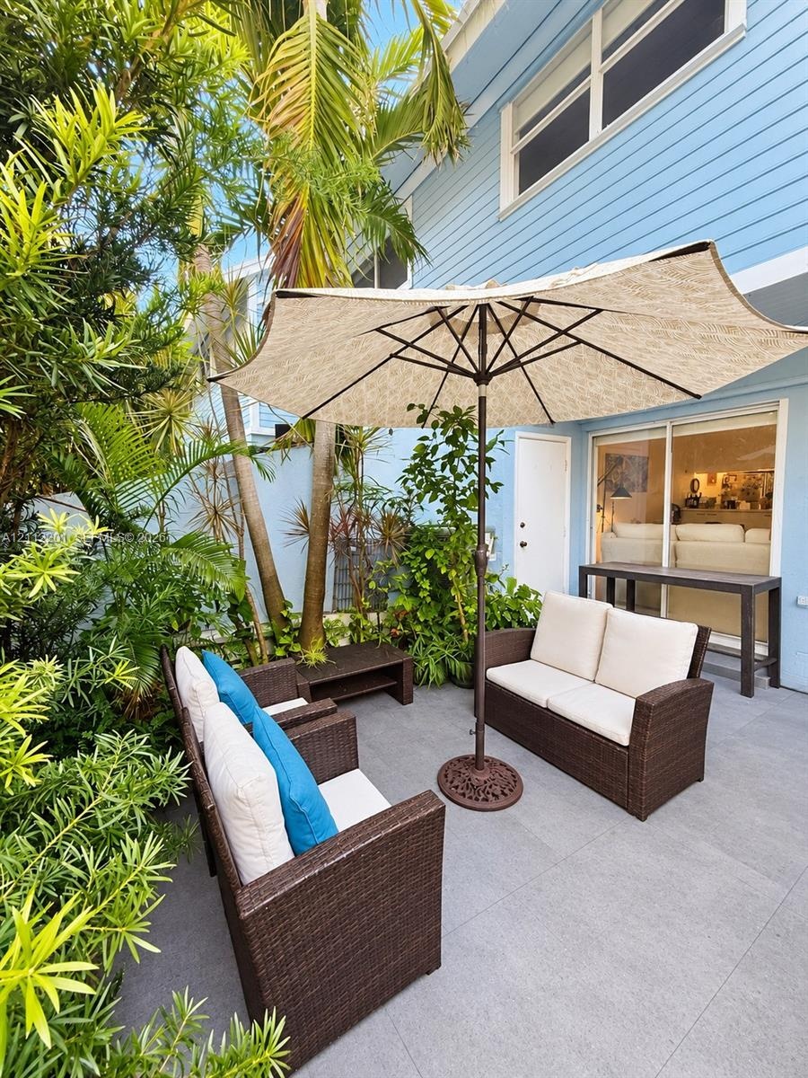 Private patio featuring light grey tile flooring, horizontal lap siding, and mature tropical landscaping