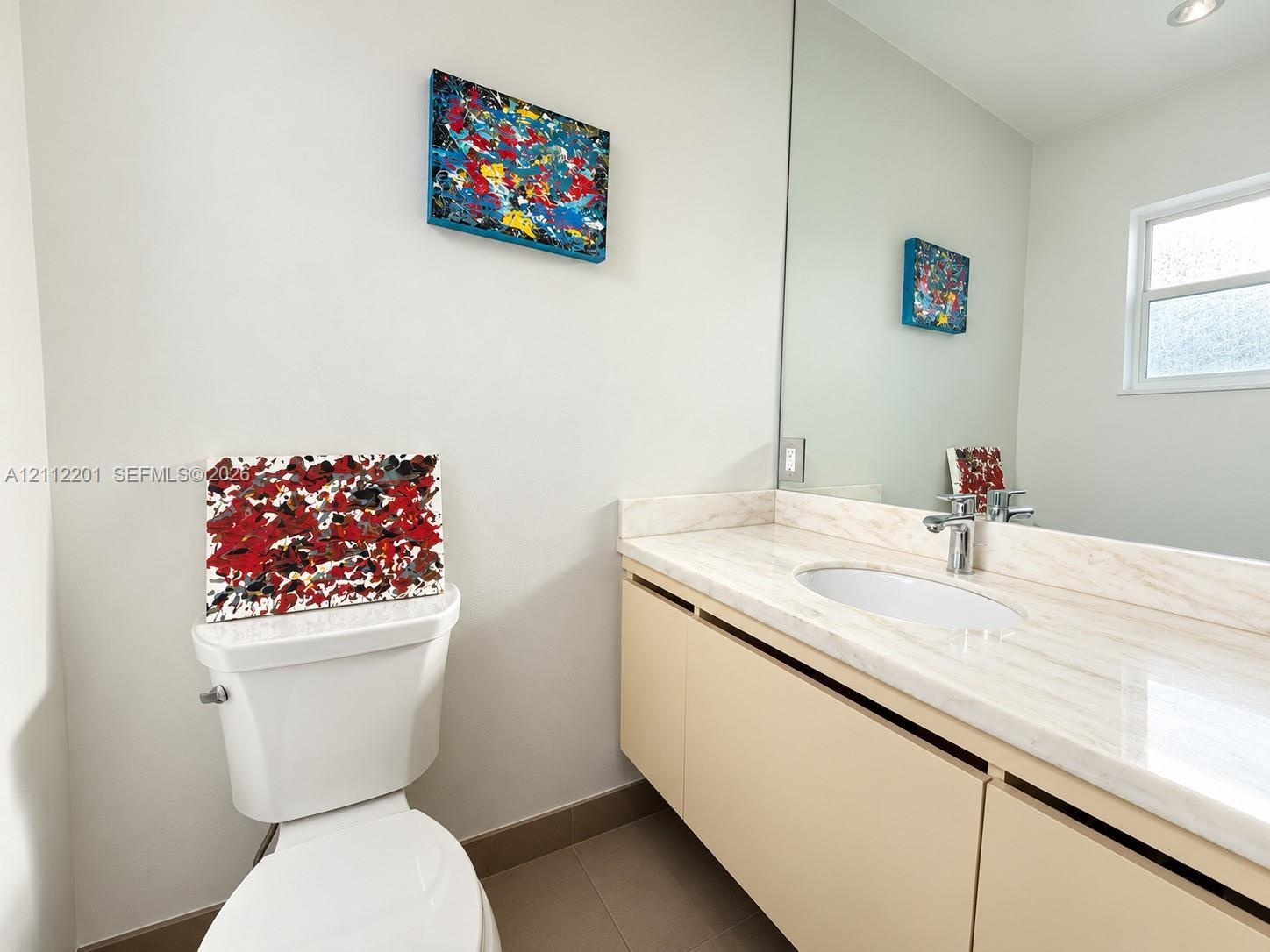 Neutral-toned vanity featuring a light-colored countertop with an integrated oval sink, polished metal faucet, floor-to-ceiling mirror, and tile floor