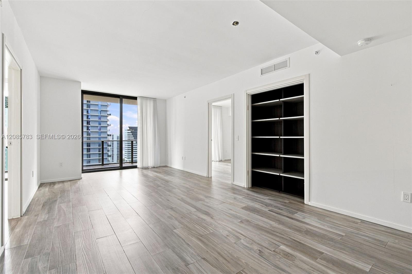 Wood-finish flooring, floor-to-ceiling glass sliding doors, built-in shelving, and recessed lighting