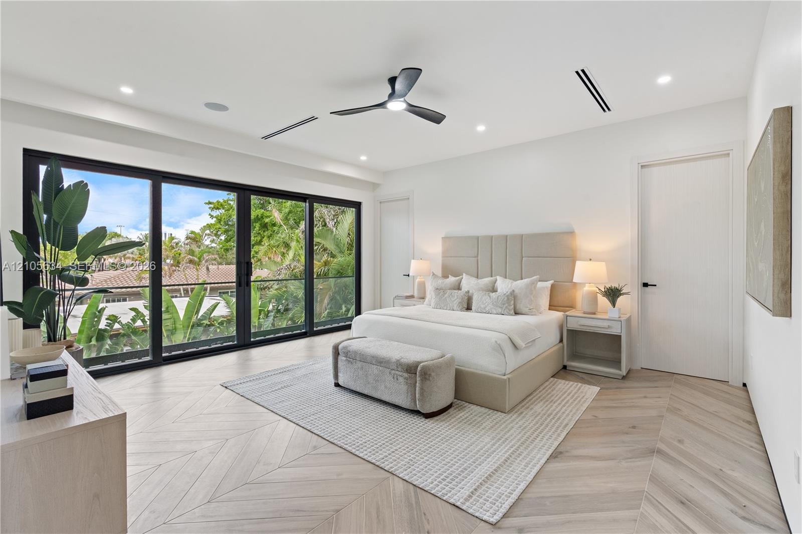 Interior space featuring chevron-patterned wood-finish flooring, floor-to-ceiling multi-panel sliding glass doors, recessed lighting, and a modern bla