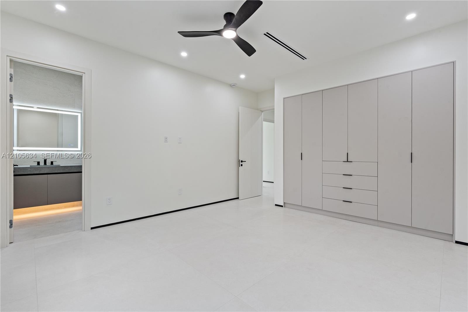Built-in floor-to-ceiling cabinetry, recessed lighting, matte black ceiling fan, and large-format tile flooring