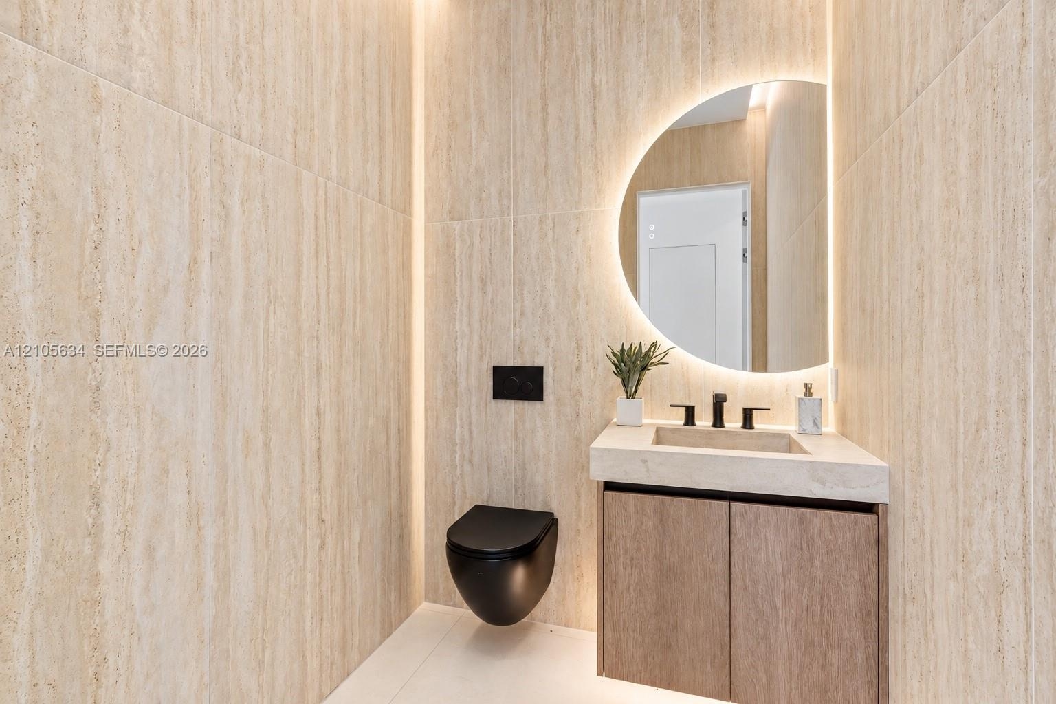 Full-height stone-finish wall tiling, wall-mounted matte black toilet, floating wood-finish vanity with integrated stone-finish basin, matte black wid