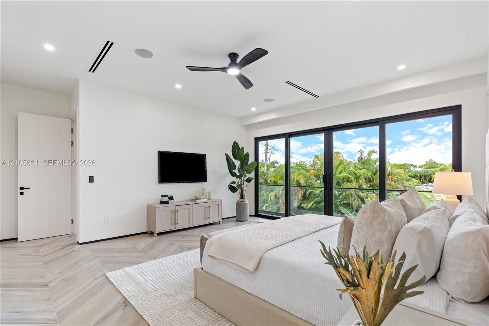 Herringbone-patterned wood-finish flooring, floor-to-ceiling glass sliding doors, recessed lighting, ceiling fan with integrated light, and built-in c