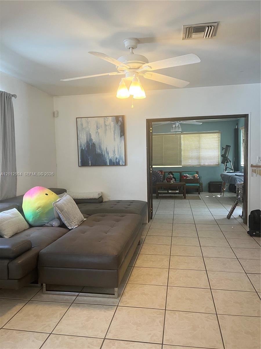 Ceramic tile flooring, white ceiling fan with integrated light fixture, and wide entryway featuring double doors