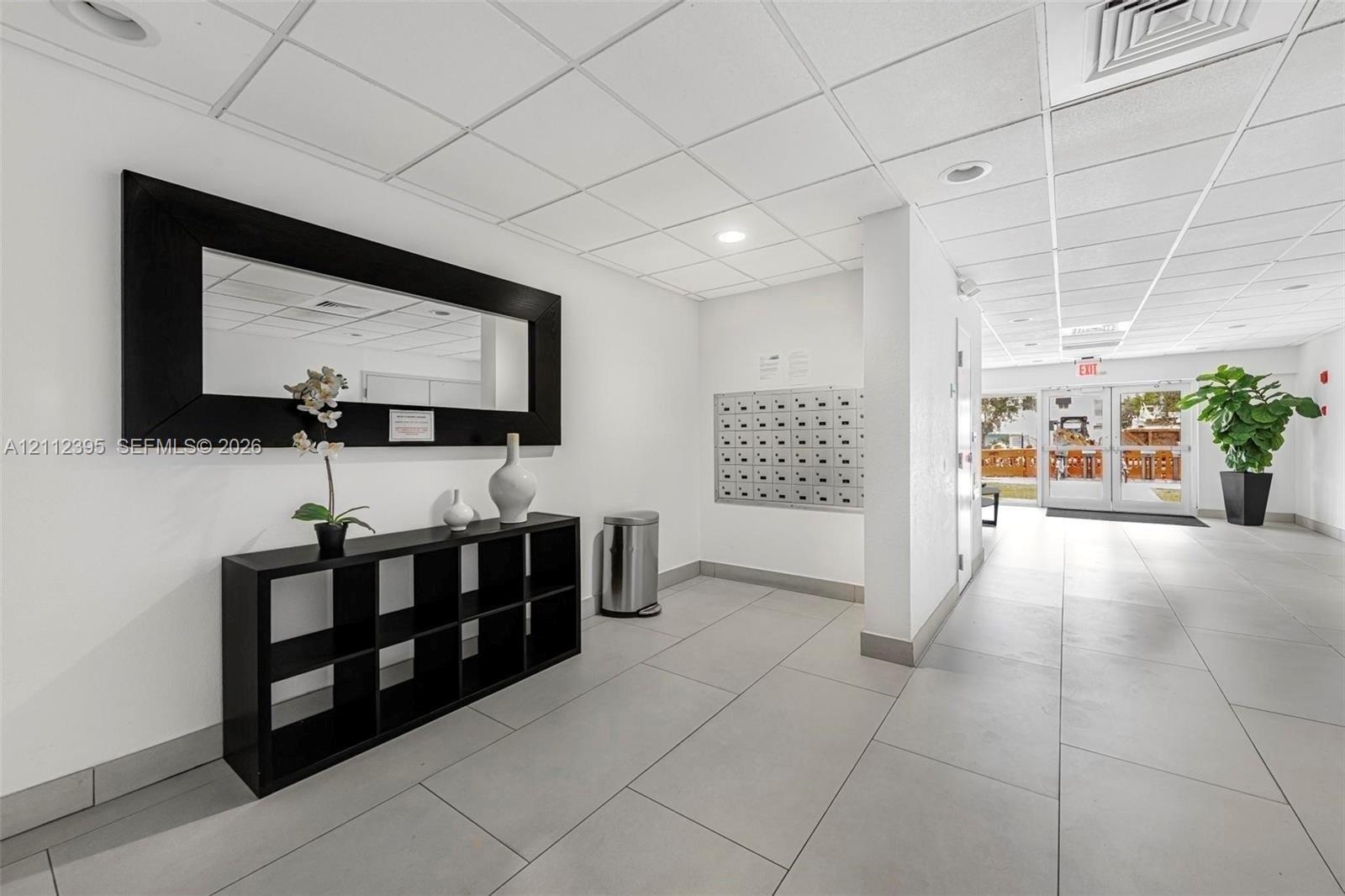 Lobby featuring tile flooring, a drop-tile ceiling with recessed lighting, and a wall-mounted metal mail station