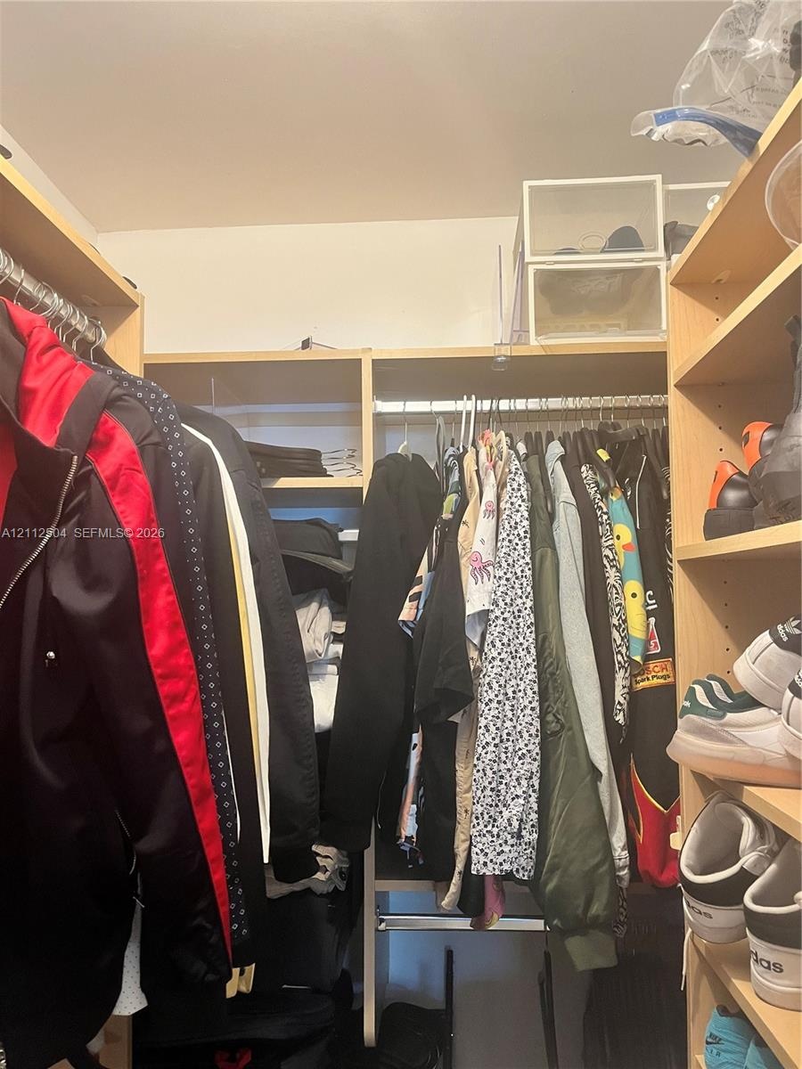 Custom walk-in closet featuring light-finish wood shelving, integrated hanging rods, and built-in vertical storage compartments