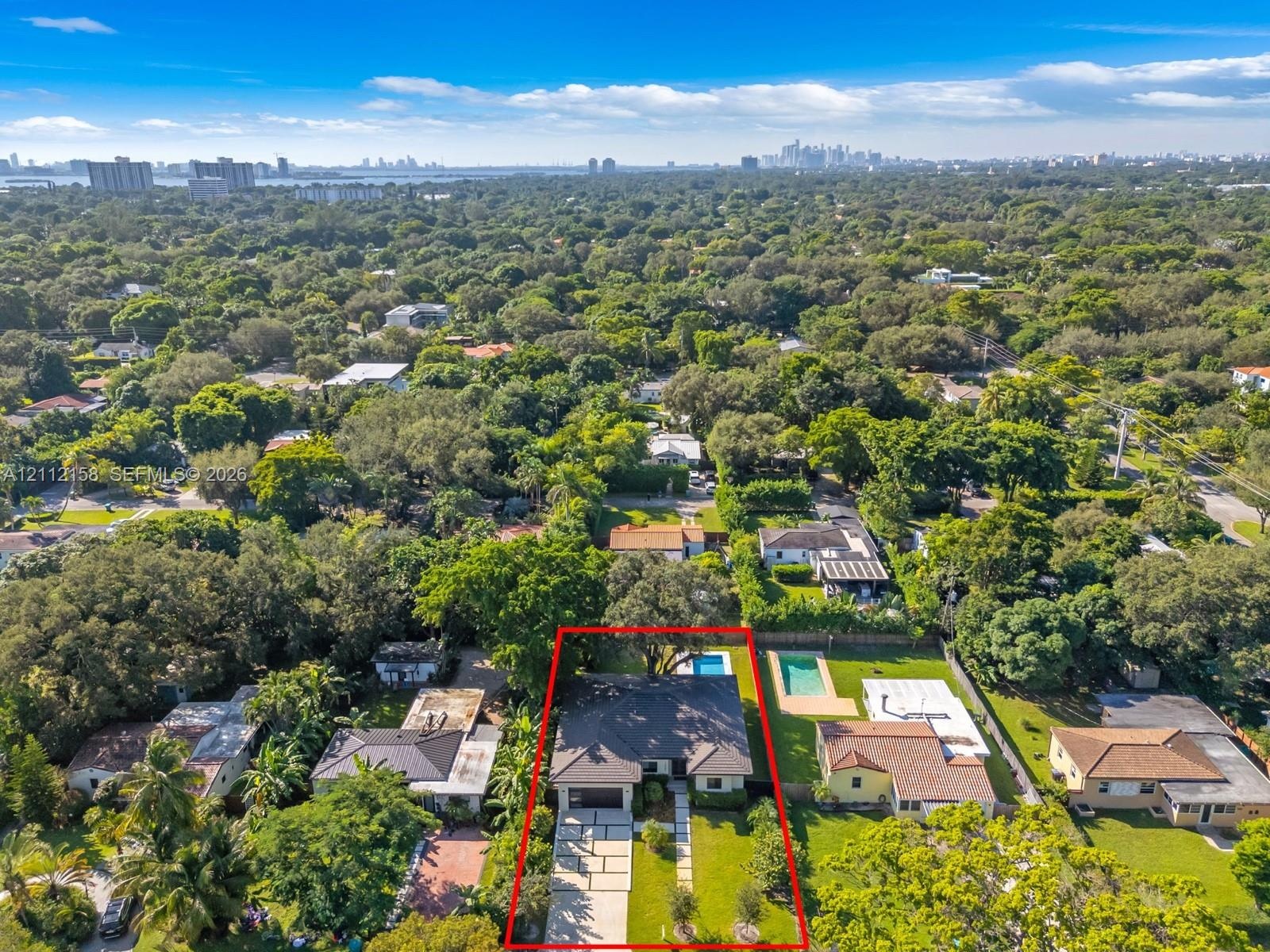 Aerial view of the single-story home with attached garage, driveway, and backyard pool