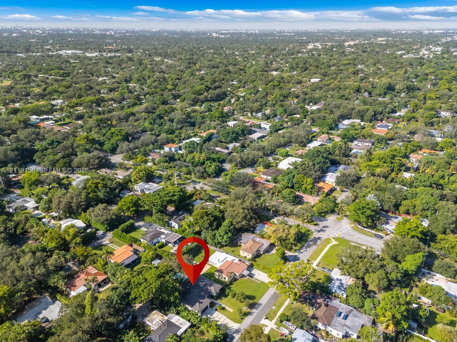 Aerial view of the property on a generous lot with a paved driveway and mature trees in a quiet, low-density neighborhood