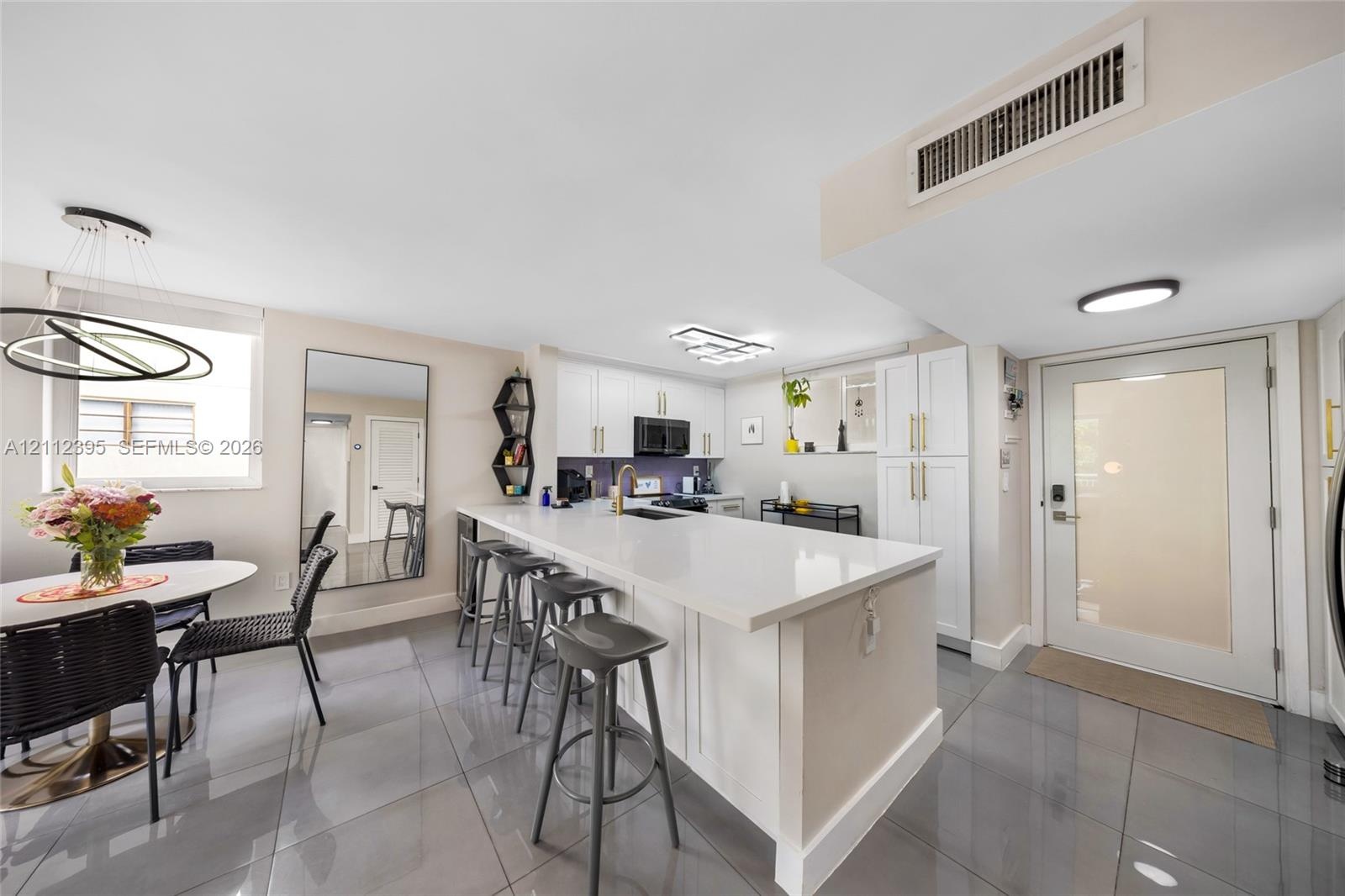 Kitchen featuring white cabinetry, solid-surface countertops, recessed lighting, and large-format tile flooring