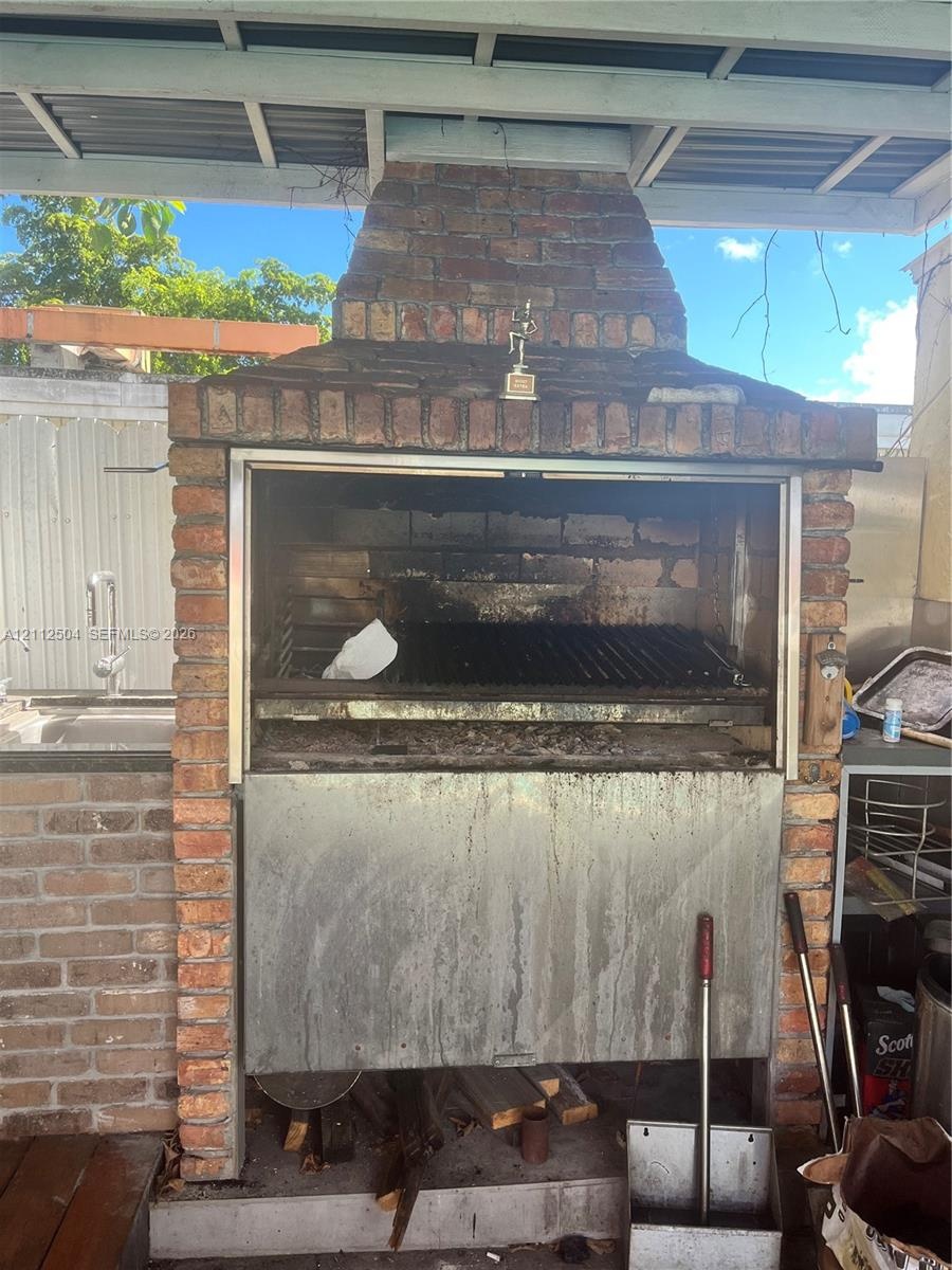 Outdoor masonry grill featuring a brick-surround hearth, integrated metal cooking grate, and stainless steel housing