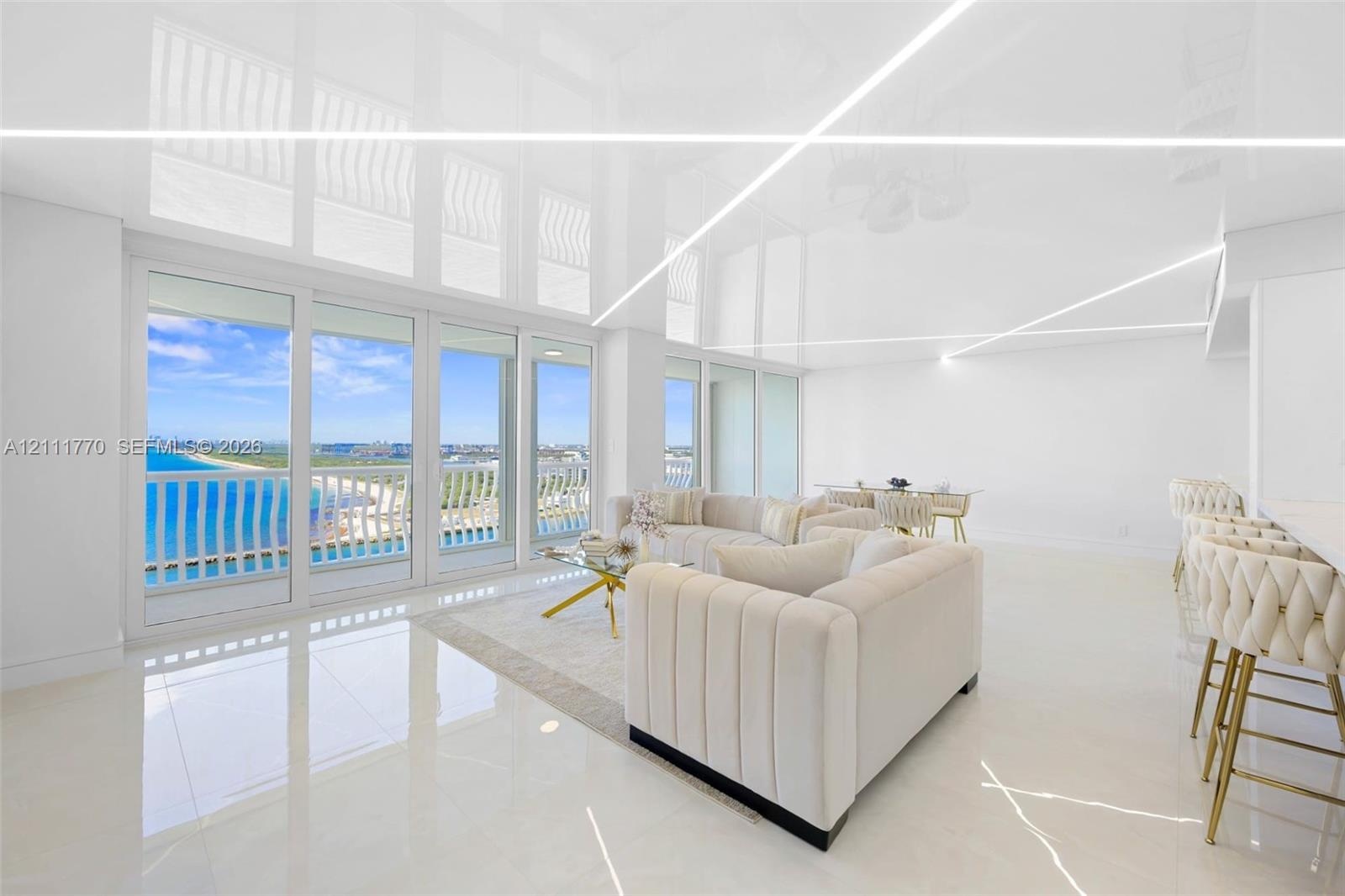 Open-concept space featuring high-gloss ceilings with recessed linear lighting, polished tile flooring, and floor-to-ceiling sliding glass doors openi
