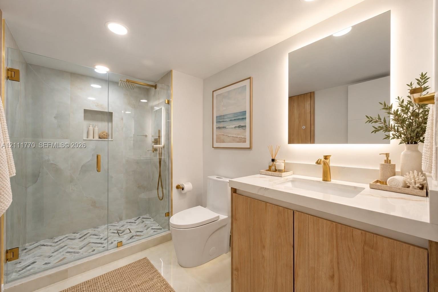 Bathroom featuring a frameless glass walk-in shower with stone tile surround, chevron-patterned floor tile, wood-finish vanity with a solid surface co