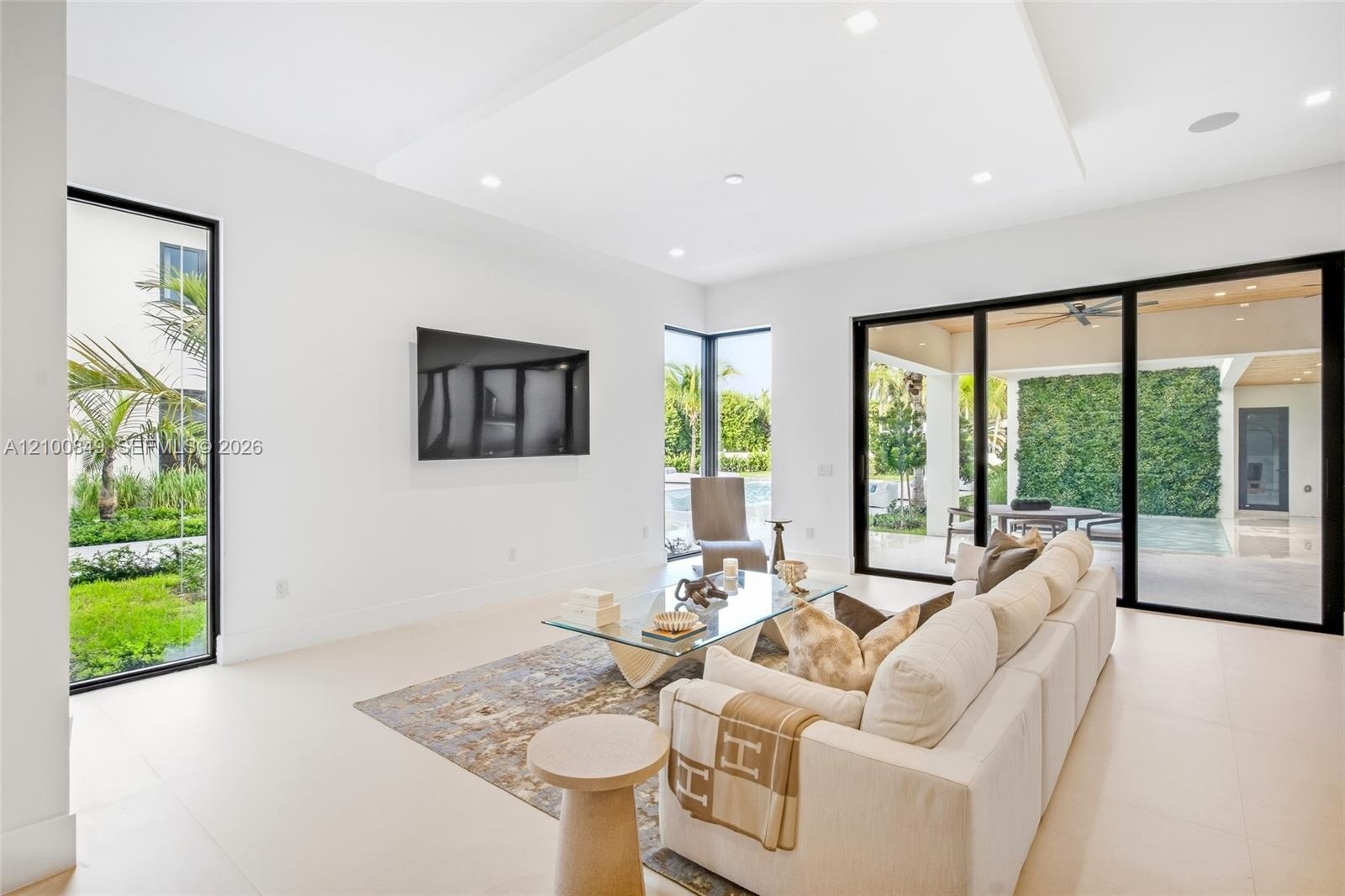 Open-concept living space featuring high ceilings with integrated recessed lighting, large-format tile flooring, a recessed ceiling detail, and floor-