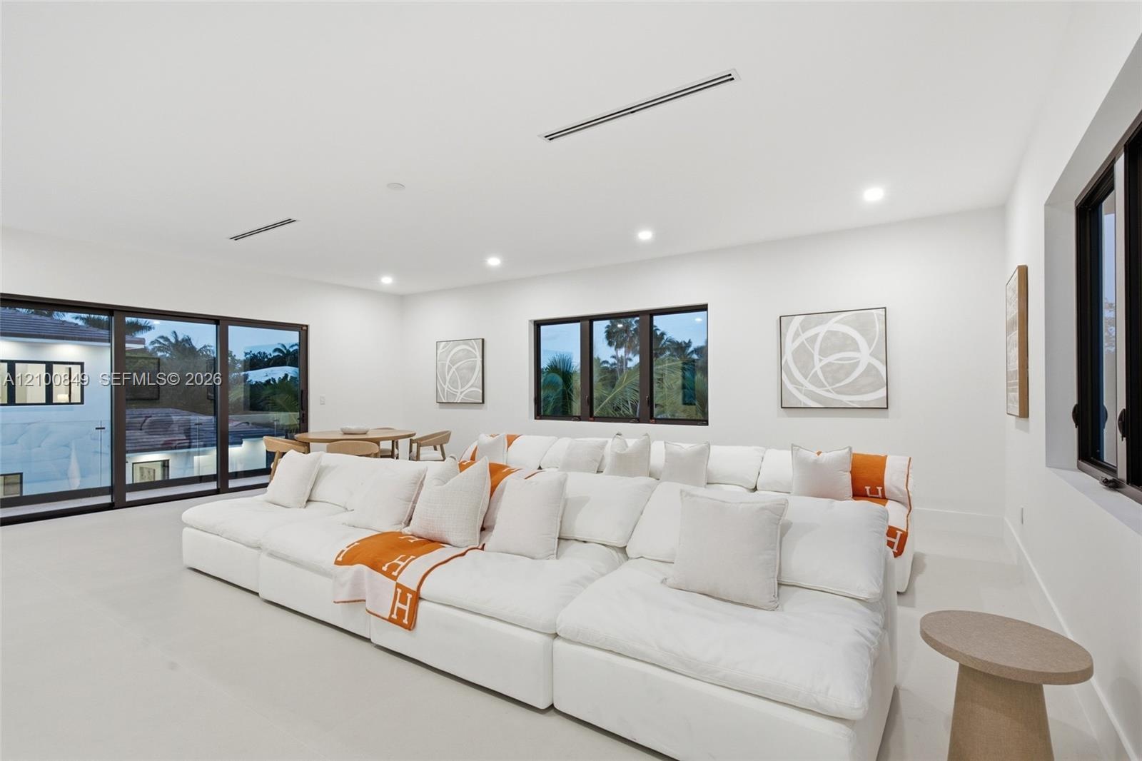 Open-concept living space featuring high ceilings, recessed lighting, expansive sliding glass doors, and dark-framed windows