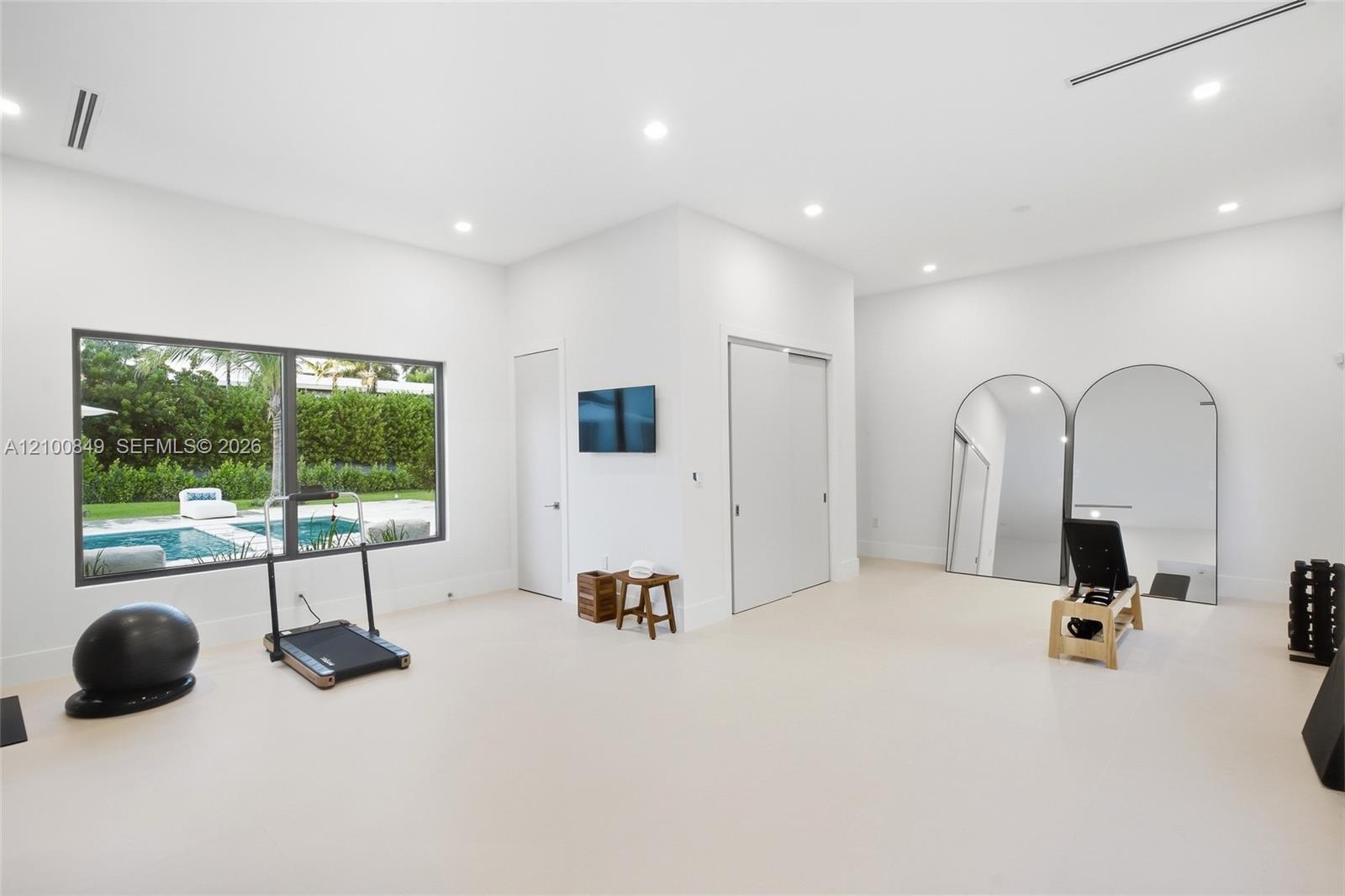 Spacious room featuring high ceilings, recessed lighting, smooth-finish flooring, and a wide window with dark metal framing