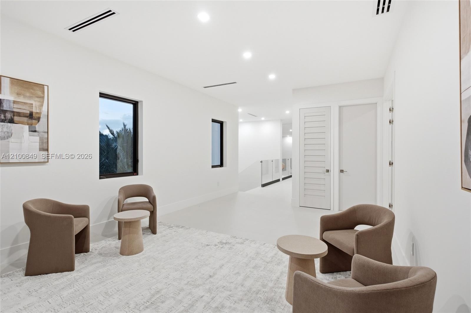 Open-concept interior space featuring recessed ceiling lighting, smooth-finish walls, high-contrast window frames, and linear ceiling registers